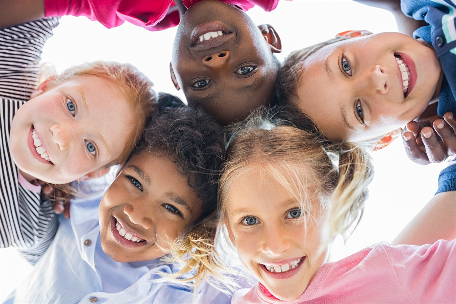 Group of smiling kids huddled together looking down at the camera