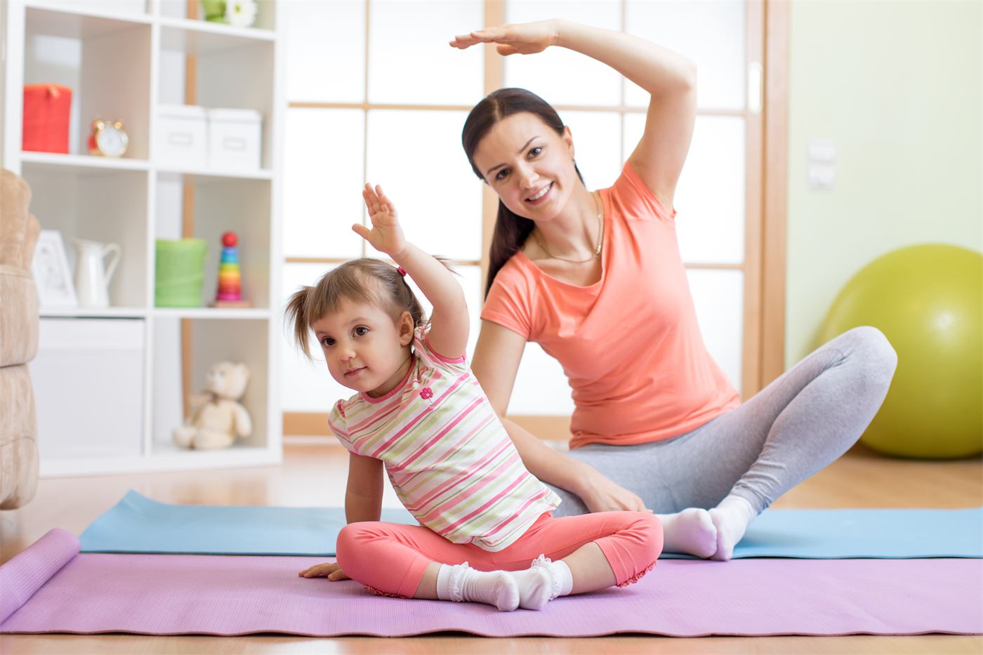 Parent and toddler stretching together on a mat