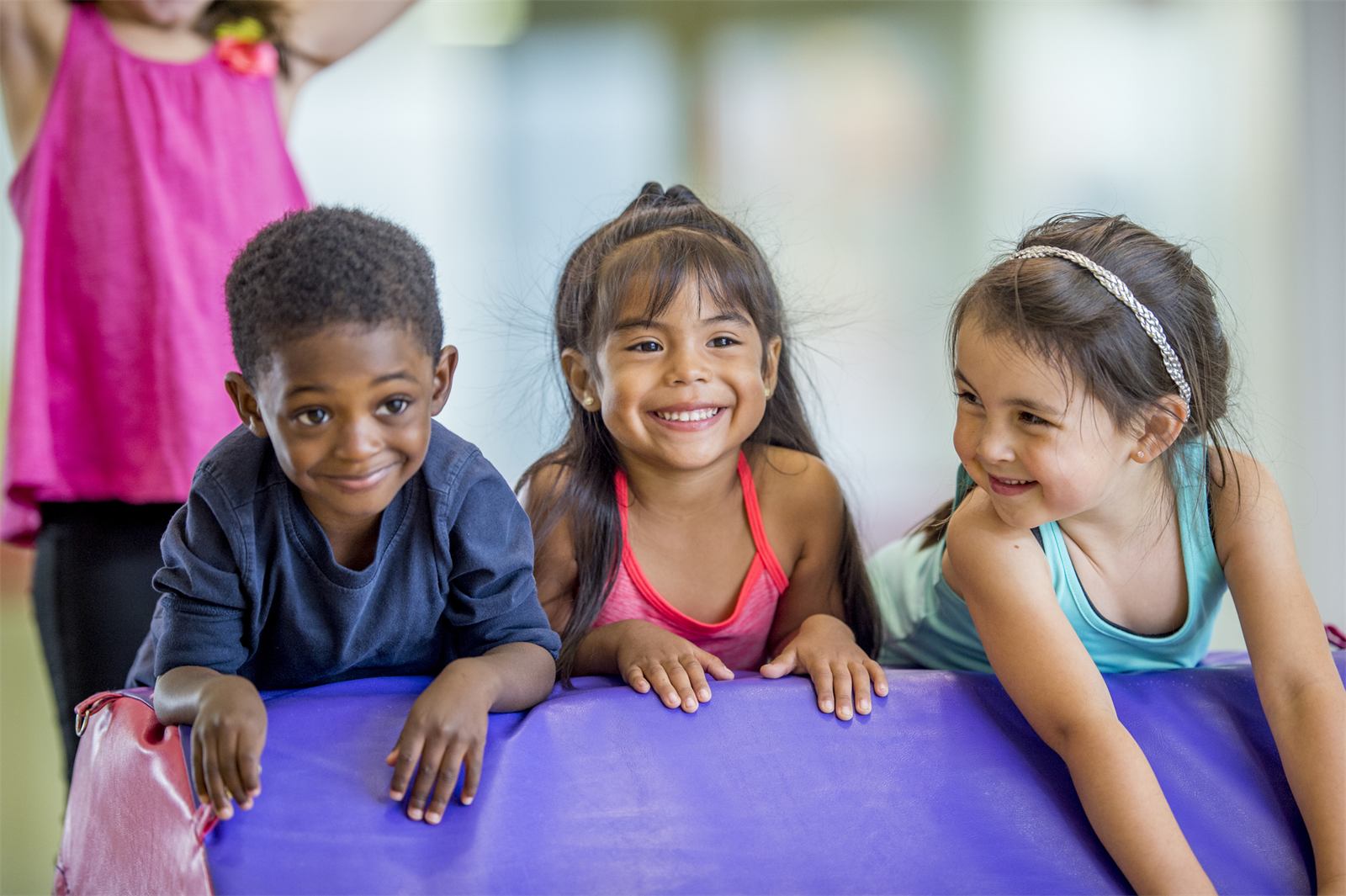 Preschoolers smiling on colorful gym mats